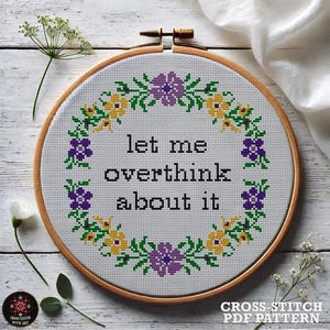 May include: Cross-stitch pattern featuring a floral wreath with purple and yellow flowers and the text "let me overthink about it".