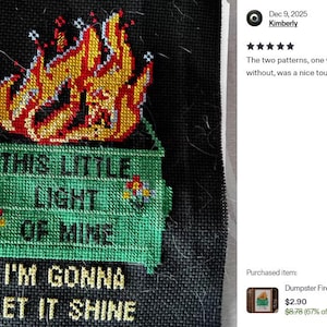Cross-stitch design on black fabric featuring a green dumpster engulfed in flames. The text reads "THIS LITTLE LIGHT OF MINE, I'M GONNA LET IT SHINE" in yellow and green. The flames are red, orange, and yellow.