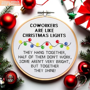 以下が含まれることがあります： 木製の輪の中に白いクロスステッチのパターンがあり、"Coworkers are like Christmas lights. They hang together, half of them don't work, some aren't very bright, but together they shine!"というテキストが書かれています。