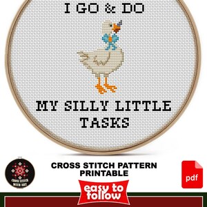 May include: A cross stitch pattern in a wooden hoop featuring a white duck with an orange beak and feet, wearing a blue bowtie. The text reads EVERY DAY I GO & DO MY SILLY LITTLE TASKS. The design size is 6 inches by 6.5 inches for AIDA 14ct fabric.