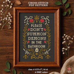 May include: Cross-stitch pattern PDF for a humorous sign that reads "Please don't summon demons in the bathroom". The sign is framed in a brown wood frame and features a skull and crossbones graphic. The pattern is 4 1/2 inches by 7 inches and uses 14 count Aida cloth with 6 DMC colours.