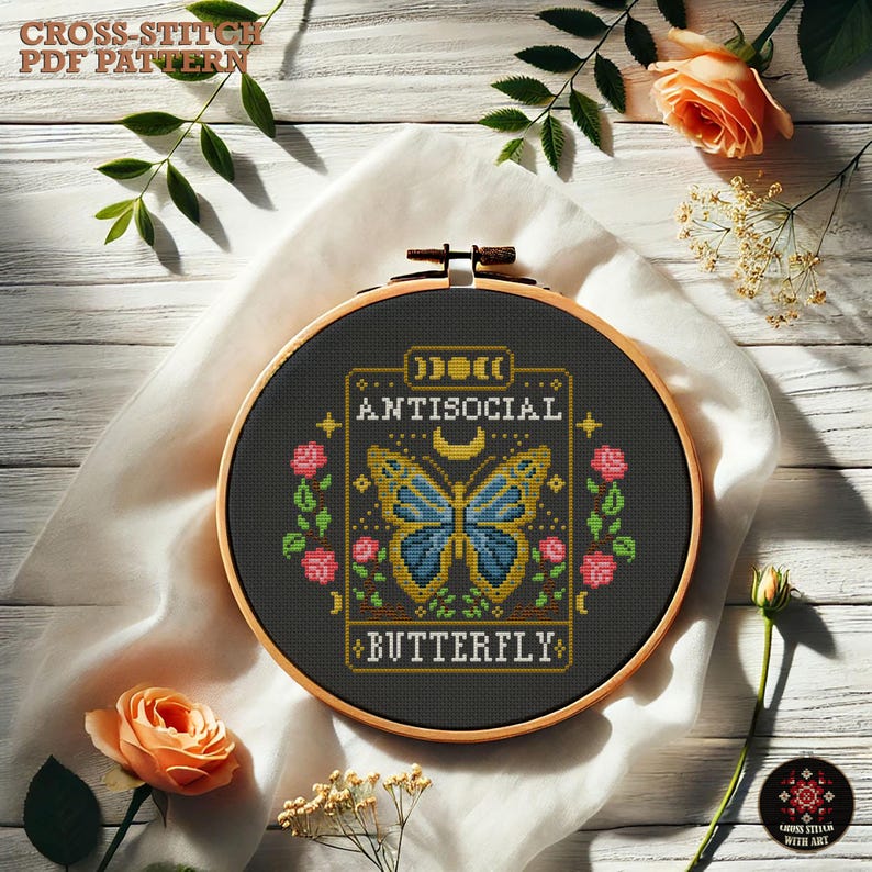 May include: A black and gold embroidery hoop with a cross-stitch design of a butterfly with the text "Antisocial Butterfly".