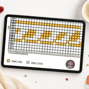 May include: A digital cross-stitch pattern displayed on a tablet. The pattern features a geometric design in gold and white. The tablet is surrounded by embroidery floss, a cup of coffee, and decorative elements.