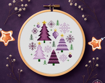 May include: A cross-stitch PDF pattern featuring a Christmas tree design in shades of purple, green, and white. The design includes Christmas trees, snowflakes, and ornaments, set within a wooden embroidery hoop. The text "CROSS-STITCH PDF PATTERN" is at the bottom.