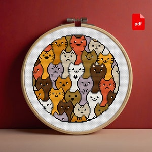 May include: A cross-stitch pattern of various cartoon cats in a circular design, framed in a wooden hoop. The cats are in shades of orange, brown, gray, and white. A red "pdf" icon is in the upper right corner.