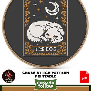 May include: A cross-stitch pattern featuring a sleeping dog, a crescent moon, and stars, framed in a wooden hoop. The design size is 8" x 12" and includes the text "THE DOG". The pattern is printable and easy to follow.