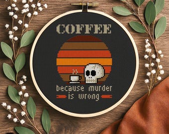 Puede incluir: Un bastidor de bordado redondo de madera que contiene un diseño de punto de cruz sobre tela negra. El diseño presenta un fondo de atardecer, una calavera blanca, una taza de café y el texto COFFEE because murder is wrong en beige y naranja.