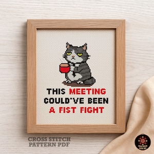 May include: Cross-stitch art in a wooden frame. The artwork features a grumpy gray cat holding a coffee cup, with the text "THIS MEETING COULD'VE BEEN A FIST FIGHT" in red and black. The phrase "CROSS STITCH PATTERN PDF" is at the bottom.