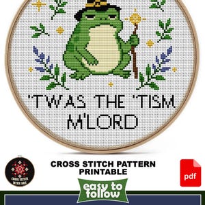 May include: Cross-stitch pattern featuring a green frog wearing a witch hat and holding a staff, with the text "'TWAS THE 'TISM M'LORD". The design is 6.5 x 6.5 inches and includes 8 DMC colors. The pattern is printable.