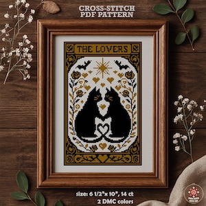 May include: A framed cross-stitch PDF pattern featuring two black cats facing each other, forming a heart with their tails. The design includes bats, stars, and floral elements in gold and black. The text "THE LOVERS" is at the top.