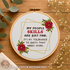 May include: A cross-stitch embroidery hoop with the text "MY PEOPLE SKILLS ARE JUST FINE. IT'S MY TOLERANCE TO IDIOTS THAT NEEDS WORK." The design includes red flowers and green leaves. The words are in black and red.
