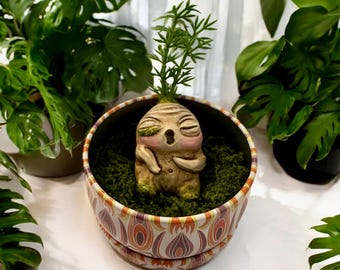 Babybeige Mandrake met roze wangen en lange stelen, met de hand gesneden en beschilderd, in zijn metalen pot met groene mosvlokken