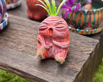 Baby Mandrake asleep, with ochre-red hues and a green and white streak