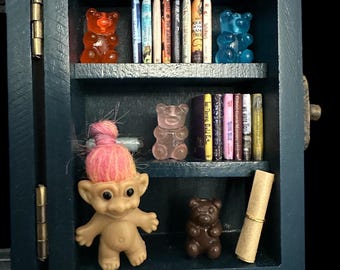 Miniatuur rariteitenkabinet uit onze kindertijd, met rozeharige trol, miniboekjes, teddyberen van hars en mysterieuze perkamenten