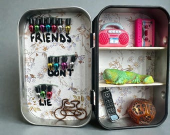 Cabinet of curiosities with nods to the Stranger Things series, including a hand-sculpted and painted Dart