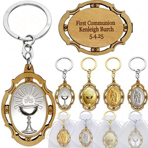 May include: A collection of wooden and metal keychains with religious symbols. The keychains feature a chalice, the Virgin Mary, and other religious imagery. One keychain has the text "First Communion Kenleigh Burch 5.4.25".