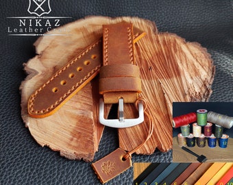 May include: Handmade brown leather watch strap with a silver buckle, displayed on a wooden surface. The strap features detailed stitching and a matching leather tag. Additional spools of thread and leather swatches are also visible.