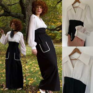 May include: A long black and white dress with a white collared top, long sleeves, and a black skirt with white trim. The dress has a fitted bodice and a flowing skirt.