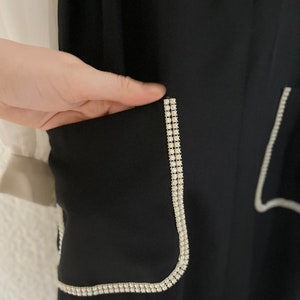 May include: Black pants with a white rhinestone trim around the pockets.