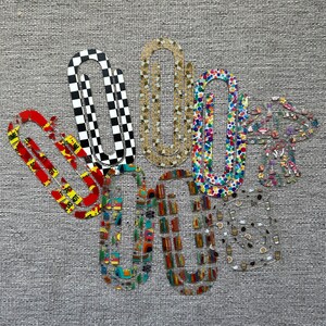 May include: Six colorful paper clips with different patterns, including checkered, polka dot, and floral designs. The clips are arranged in a cluster on a gray textured background.