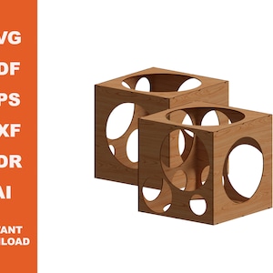 Puede incluir: Dos cubos de madera con intrincados recortes circulares. Los cubos están apilados uno encima del otro, con el cubo superior ligeramente desplazado hacia la derecha. Los cubos son de color marrón claro y tienen un acabado liso y pulido.