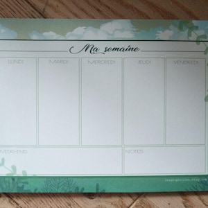 May include: A green and blue weekly planner with a nature-inspired design. The planner has sections for each day of the week, including Monday, Tuesday, Wednesday, Thursday, Friday, Saturday, and Sunday. The planner also has a section for notes.