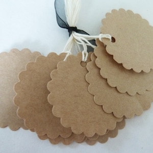 Peut inclure: Un ensemble d'étiquettes en papier marron à bord festonné, attachées avec de la ficelle blanche et un ruban noir. Ces étiquettes vierges sont idéales pour l'étiquetage ou le bricolage. Parfait pour les cadeaux ou les créations.