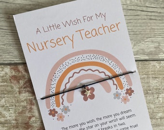 May include: A card with a rainbow design and the text "A Little Wish For My Nursery Teacher". The card is attached to a string bracelet with a small gold star charm. The text on the card reads: "The more you wish, the more you dream. The bigger the star on your wrist will seem. When the cord breaks in two, All your dreams and wishes will come true! (Or so they say)"
