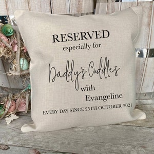 May include: A beige linen cushion with black text that reads "RESERVED especially for Daddy's Cuddles with Evangeline EVERY DAY SINCE 25TH OCTOBER 2021".