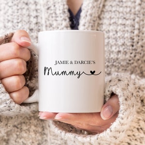 May include: White ceramic mug with black text that reads "Jamie & Darcie's Mummy" with a small heart symbol.