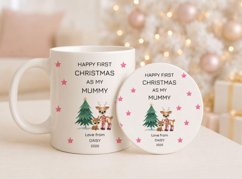 May include: A white ceramic mug and a matching round coaster, both featuring the text "HAPPY FIRST CHRISTMAS AS MY MUMMY", "Love from DAISY", and "2026". The design includes a green Christmas tree, two reindeer, and small pink stars.