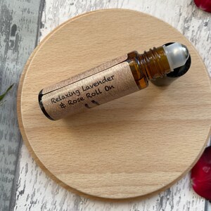 May include: A brown glass roll-on bottle with a silver roller ball. The bottle is labelled "Relaxing Lavender & Rose Roll On".