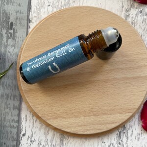 May include: A brown glass roll-on bottle with a blue label that says "De-stress Bergamot & Geranium Roll On".