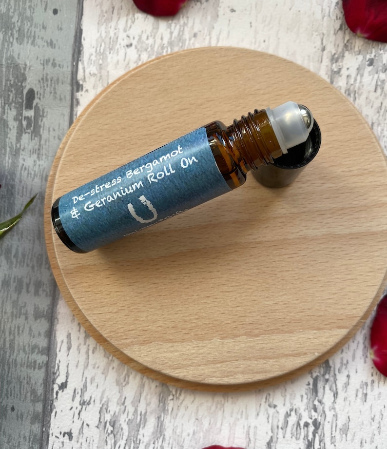 May include: A brown glass roll-on bottle with a blue label that says "De-stress Bergamot & Geranium Roll On".