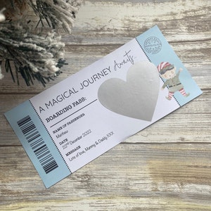 May include: A blue and white boarding pass with a silver heart and the text "A Magical Journey Awaits... Boarding Pass: Name of Passenger: Matthew Date: 22nd December 2022 Message: Lots of love, Mummy & Daddy XXX"