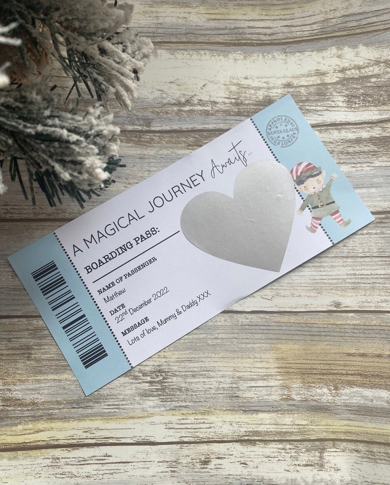 May include: A blue and white boarding pass with a silver heart and the text "A Magical Journey Awaits... Boarding Pass: Name of Passenger: Matthew Date: 22nd December 2022 Message: Lots of love, Mummy & Daddy XXX"