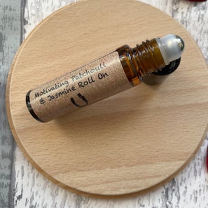 May include: A brown glass roll-on bottle with a silver roller ball. The bottle is labelled "Motivating Patchouli & Jasmine Roll On".