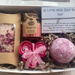 Puede incluir: Una caja de regalo llena de productos para el ba&ntilde;o y el cuerpo. La caja contiene una bomba de ba&ntilde;o rosa, un jab&oacute;n de rosa en forma de coraz&oacute;n, un peque&ntilde;o frasco de sales de ba&ntilde;o con p&eacute;talos de rosa y una vela de soja con la etiqueta "Midnight Rose". Se incluye una peque&ntilde;a tarjeta con el texto "A Little Wish Just For You!" Cuanto m&aacute;s deseas, m&aacute;s sue&ntilde;as. Cuanto m&aacute;s grande sea la estrella en tu mu&ntilde;eca, m&aacute;s parecer&aacute;. Cuando el cord&oacute;n se rompa en dos. Todos tus sue&ntilde;os y deseos se har&aacute;n realidad.
