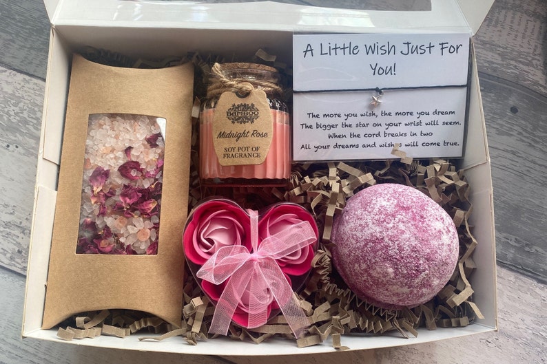 Puede incluir: Una caja de regalo llena de productos para el ba&ntilde;o y el cuerpo. La caja contiene una bomba de ba&ntilde;o rosa, un jab&oacute;n de rosa en forma de coraz&oacute;n, un peque&ntilde;o frasco de sales de ba&ntilde;o con p&eacute;talos de rosa y una vela de soja con la etiqueta "Midnight Rose". Se incluye una peque&ntilde;a tarjeta con el texto "A Little Wish Just For You!" Cuanto m&aacute;s deseas, m&aacute;s sue&ntilde;as. Cuanto m&aacute;s grande sea la estrella en tu mu&ntilde;eca, m&aacute;s parecer&aacute;. Cuando el cord&oacute;n se rompa en dos. Todos tus sue&ntilde;os y deseos se har&aacute;n realidad.