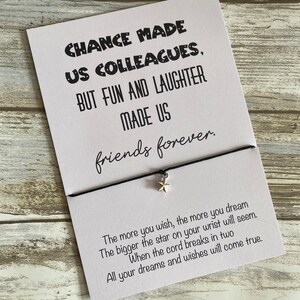 May include: A white card with black text that reads "Chance made us colleagues, but fun and laughter made us friends forever."  The card is attached to a black string with a silver star charm. The text below the card reads "The more you wish, the more you dream. The bigger the star on your wrist will seem. When the cord breaks in two, all your dreams and wishes will come true."