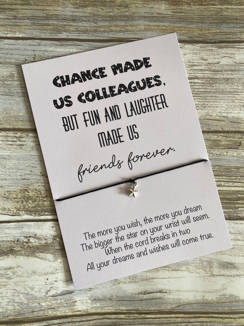 May include: A white card with black text that reads "Chance made us colleagues, but fun and laughter made us friends forever."  The card is attached to a black string with a silver star charm. The text below the card reads "The more you wish, the more you dream. The bigger the star on your wrist will seem. When the cord breaks in two, all your dreams and wishes will come true."