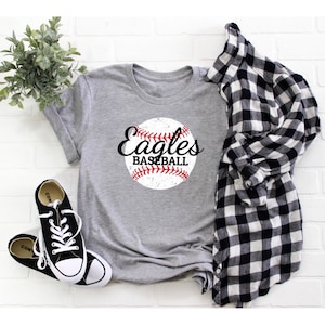 May include: Gray t-shirt with a distressed white baseball graphic and the text "Eagles Baseball" in black.