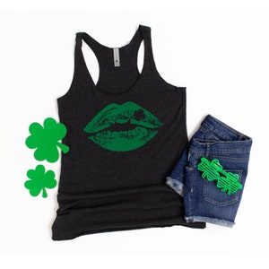 Puede incluir: Un top de tirantes gris oscuro con un estampado de labios verdes y un dise&ntilde;o de tr&eacute;bol. El top de tirantes est&aacute; hecho de un material suave y c&oacute;modo.