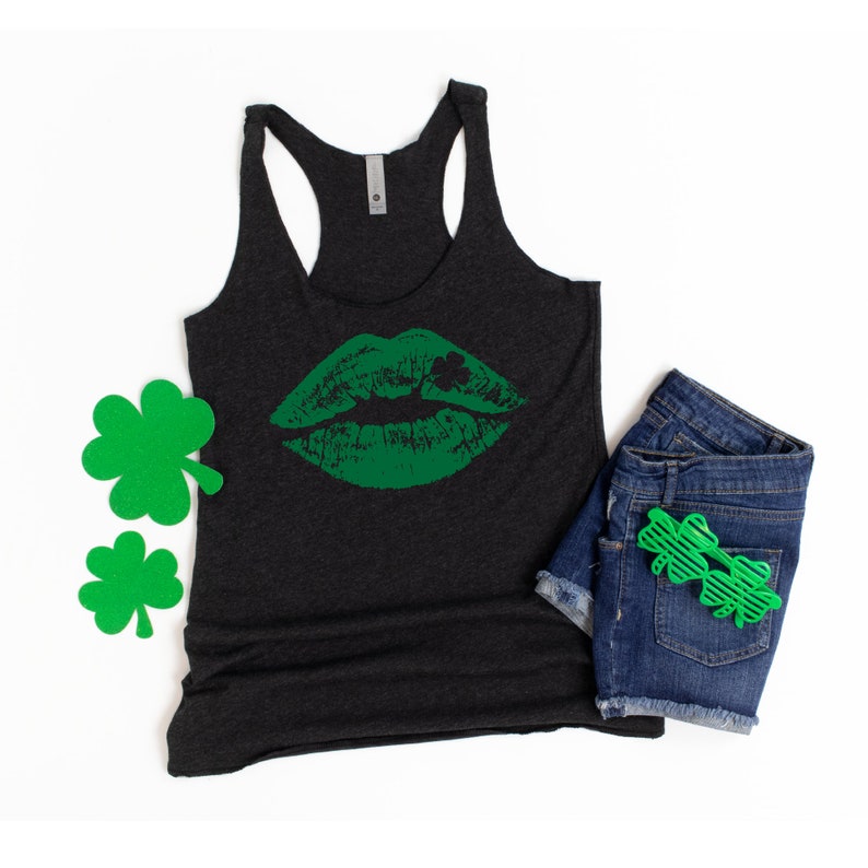 Puede incluir: Un top de tirantes gris oscuro con un estampado de labios verdes y un dise&ntilde;o de tr&eacute;bol. El top de tirantes est&aacute; hecho de un material suave y c&oacute;modo.