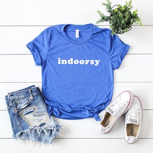 K&ouml;nnte beinhalten: Ein k&ouml;nigsblaues T-Shirt mit dem Wort "indoorsy" in wei&szlig; auf der Vorderseite. Das Shirt ist aus einem weichen, bequemen Material und perfekt f&uuml;r den Alltag.