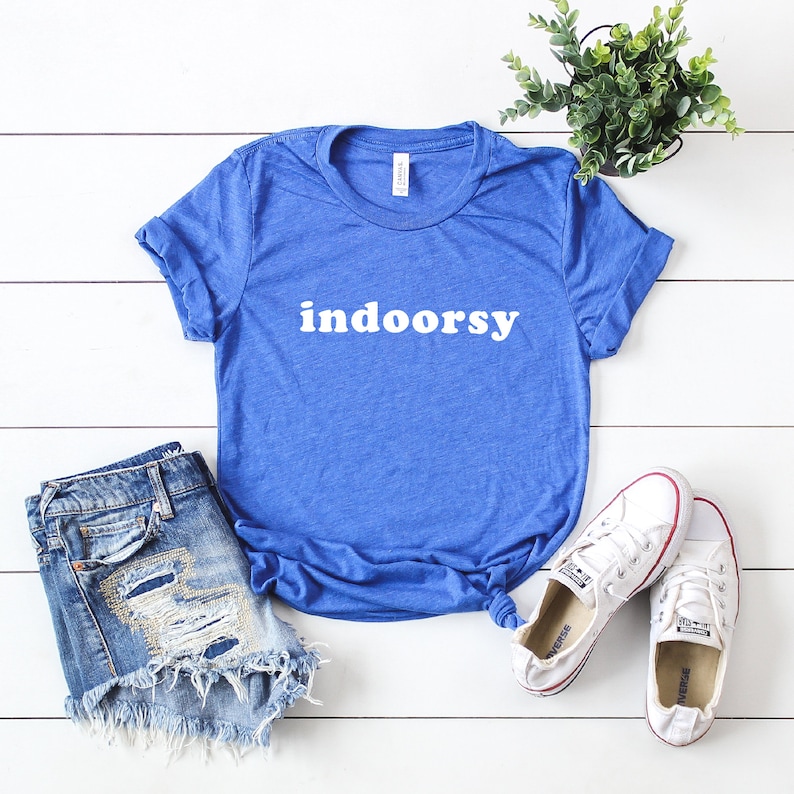 K&ouml;nnte beinhalten: Ein k&ouml;nigsblaues T-Shirt mit dem Wort "indoorsy" in wei&szlig; auf der Vorderseite. Das Shirt ist aus einem weichen, bequemen Material und perfekt f&uuml;r den Alltag.