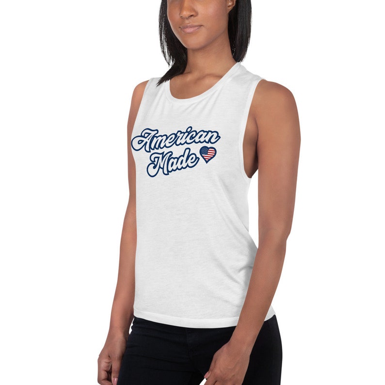 May include: White muscle tank top with the text "American Made" in blue script with a red, white, and blue heart with an American flag design.