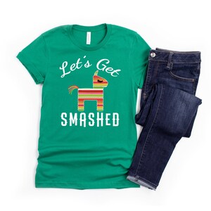 May include: A green t-shirt with a white graphic of a pinata and the text "Let's Get Smashed".