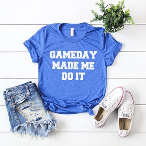 May include: A royal blue t-shirt with the text "GAMEDAY MADE ME DO IT" in white distressed lettering.