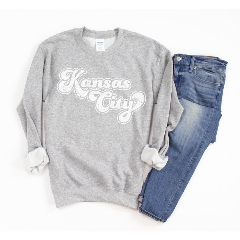 May include: A gray sweatshirt with a white retro-style graphic that says "Kansas City".
